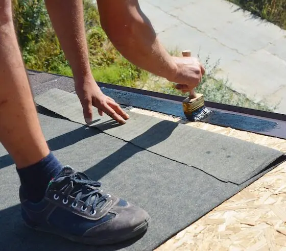 Person installing roof waterproofing membrane