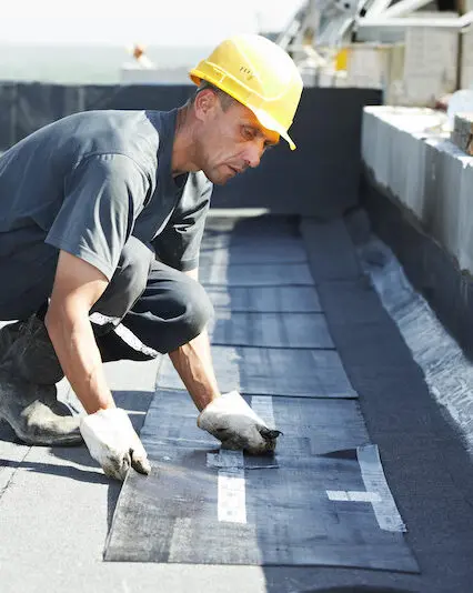 Worker installing waterproof roofing material