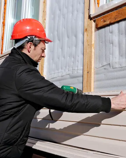 Worker installing house siding construction