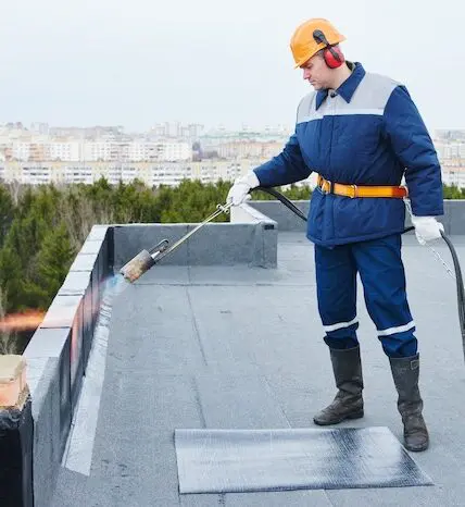 Roofer applying waterproof membrane rooftop